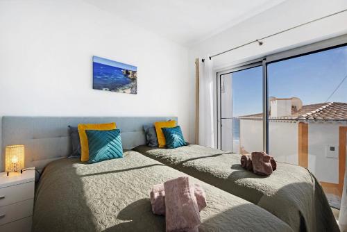 two beds in a room with a large window at Casinha in Burgau