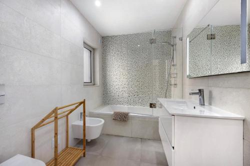 a white bathroom with a tub and a sink at Casinha in Burgau