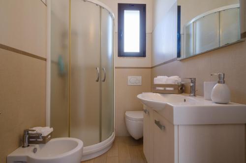 a bathroom with a shower and two sinks and a toilet at Villa Scoglio in Melendugno