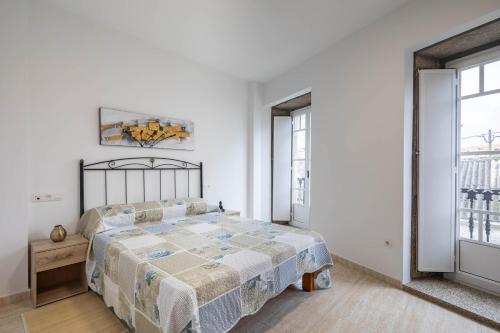a white bedroom with a bed and two windows at Valle Inclan in Villanueva de Arosa