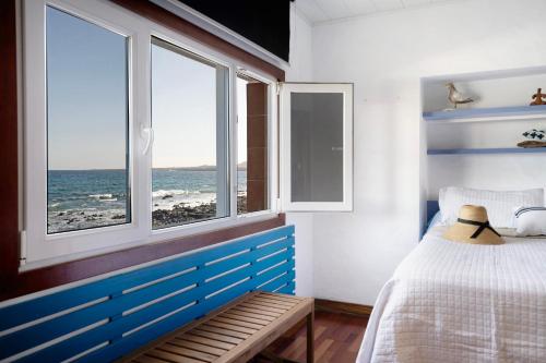 a bedroom with a bed and two windows with the ocean at El Mar y Tú in Arrieta