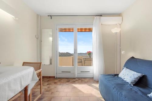 a bedroom with a blue couch and a sliding glass door at Le Mas Berliat N°9 in Bormes-les-Mimosas