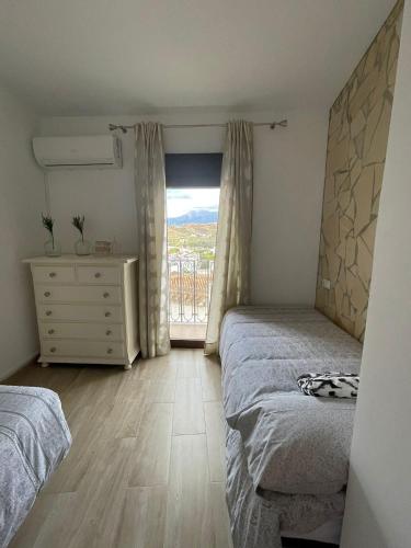 a bedroom with two beds and a dresser and a window at La morena in Guaro