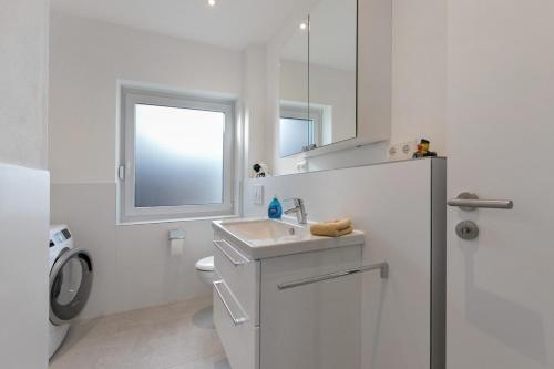 a white bathroom with a sink and a mirror at Seelenwärmerstuuv in Kronprinzenkoog