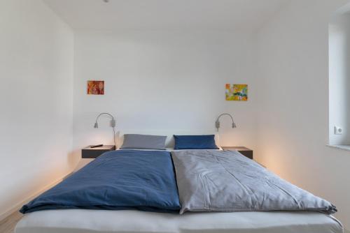 a bedroom with a bed with blue sheets and two lamps at Seelenwärmerstuuv in Kronprinzenkoog