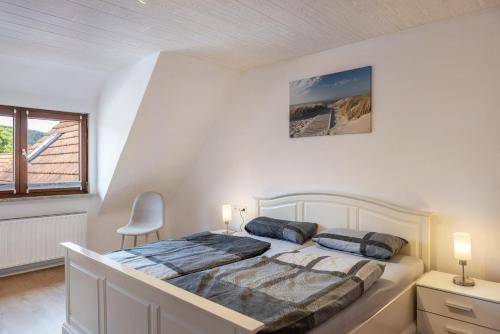 a white bedroom with a bed and a window at Ferienwohnung Hennen in Witzenhausen