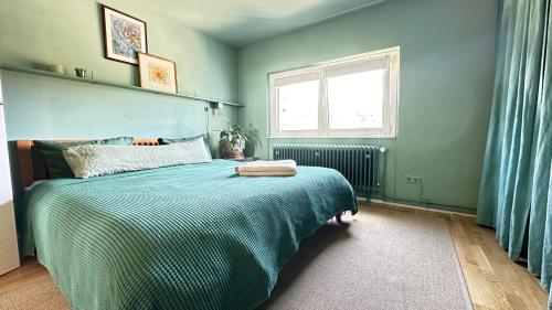 a bedroom with a bed with a green comforter and a window at Bayerwaldresort in Sankt Englmar