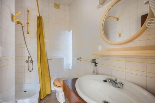a bathroom with a sink and a toilet and a mirror at Apartamento Amarelo T1 in Odeceixe