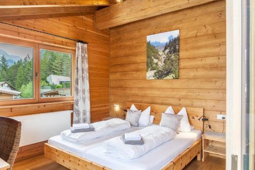 two beds in a room with wooden walls and windows at Mountainlodge in Leutasch