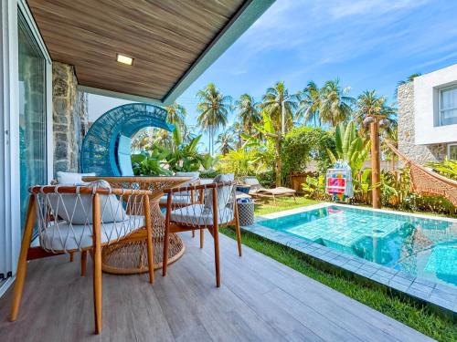 an outdoor patio with a table and chairs next to a swimming pool at Casa Verde Mar Naluum in Passo de Camarajibe