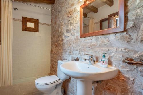 a bathroom with a sink and a toilet and a mirror at S'era in Santanyi