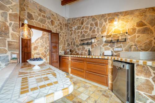 a kitchen with stone walls and a sink and a dishwasher at Casa Sol y Luna in Artá