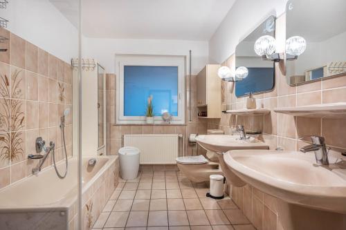 a bathroom with two sinks and a tub and a toilet at Ferienhaus Timm in Meldorf