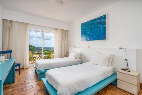 two beds in a room with a window at Alto da Lua in Bordeira