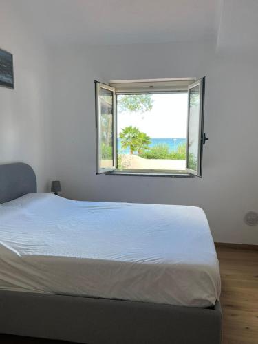 a white bedroom with a bed and a window at Villa Edith in Parghelia