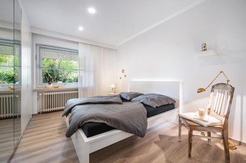 a white bedroom with a bed and a chair at Ferienhaus Auszeit Meer in Cuxhaven
