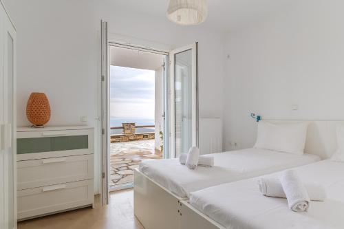 a bedroom with two beds and a view of the ocean at Vassilis Family Villa Tinos in Triandáros