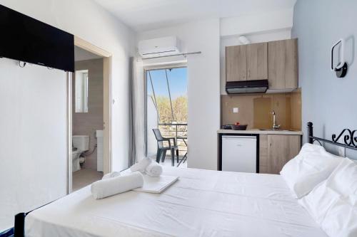ein Schlafzimmer mit einem weißen Bett und eine Küche in der Unterkunft Iguana studio 2 in Preveza