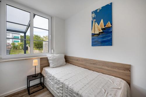 a bedroom with a bed and a painting of sailboats at Ferienbungalow Süssau in Süssau