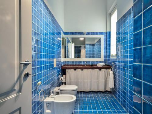a blue tiled bathroom with a toilet and a sink at Li Conchi 13 in Castiadas