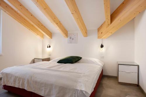 a bedroom with a bed with white sheets and wooden ceilings at Cà Dei Nane Vermiglio in Vermiglio