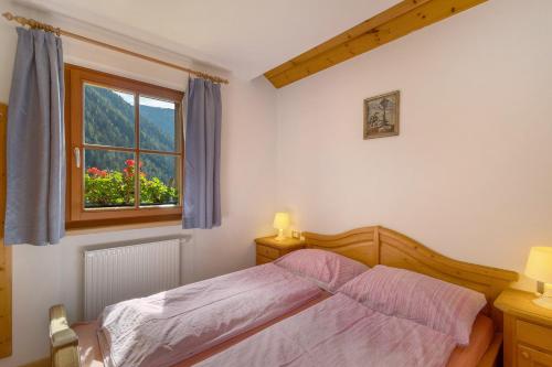 a bedroom with a bed and a window at Inneroswalderhof in Anterselva di sotto