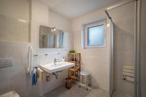 a white bathroom with a sink and a shower at Silbernagl sonnig mit Gartenblick in Issengo