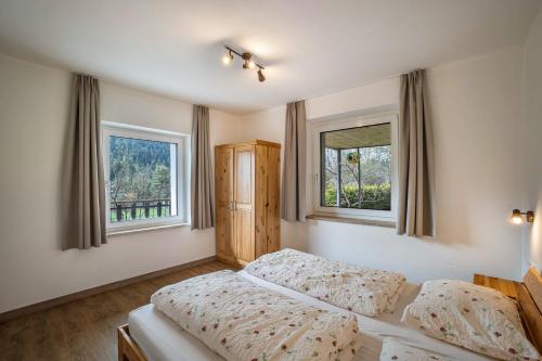 a bedroom with two beds and two windows at Silbernagl sonnig mit Gartenblick in Issengo