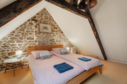a bed in a room with a stone wall at Maison Plage Verger Cancale in Cancale