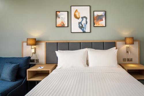 a bedroom with a bed and a blue couch at Delta Hotels by Marriott Milton Keynes in Milton Keynes