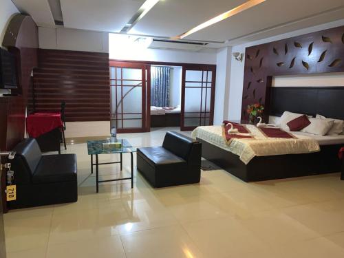 a bedroom with a bed and a couch and a chair at Hotel Rose Garden in Chittagong