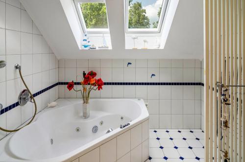 a bathroom with a tub with red flowers in a vase at Ferienwohnung Bodenstein in Surwold