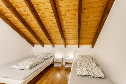 two beds in a room with a wooden ceiling at Ferienwohnung Rinke in Schmallenberg