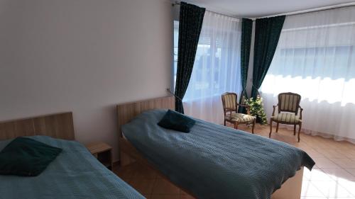 ein Schlafzimmer mit zwei Betten, Stühlen und einem Fenster in der Unterkunft Bele House in Karmėlava