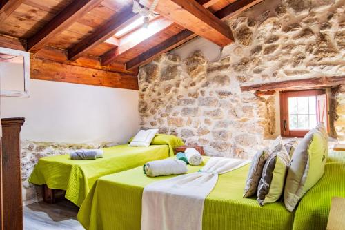 two beds in a room with a stone wall at La Cantina in Villar de Corneja