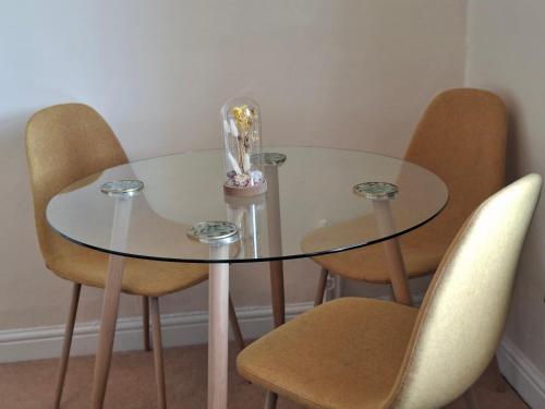 a glass table with four chairs and a vase on it at Pulteney Road Apartment in Bath