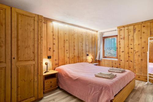 a bedroom with a bed with wooden walls and a window at Les Cles - Genepy in Valsavarenche