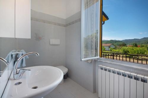 a white bathroom with a sink and a window at Da Dri´ in Brugnato