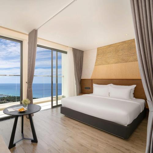 a bedroom with a large bed and large windows at Apec Beach Luxury Phú Yên in Tuy Hoa