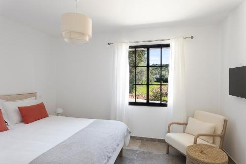 a white bedroom with a bed and a window at Villa Catherine in Ghisonaccia