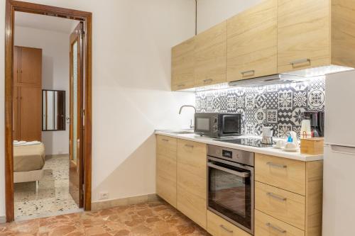 a kitchen with wooden cabinets and a microwave at Vito 80 in Chiaramonte Gulfi