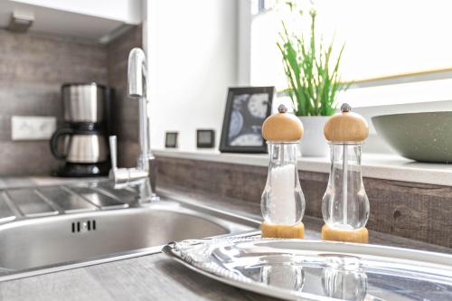 two glass bottles with wooden tops sitting on a kitchen sink at Mika in Oesterdeichstrich