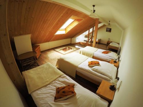 a attic room with three beds and a window at Pensjonat Tajemniczy Ogród in Frydman