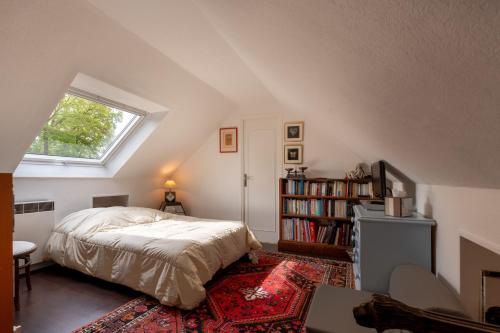 a attic bedroom with a bed and a window at Ty Clafout wifi parking in Saint-Nolff