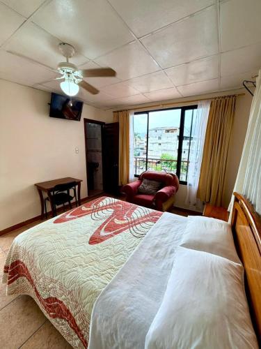 a bedroom with a bed and a chair and a window at Hotel Nivel 5 in Macas
