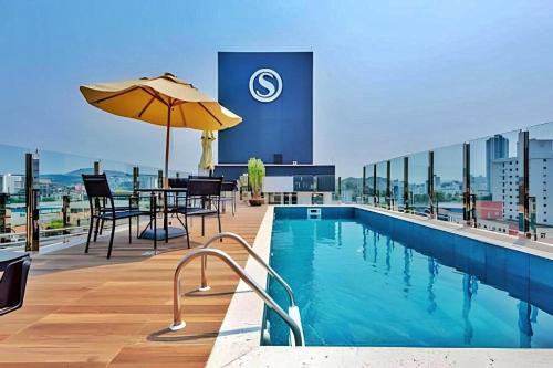 a pool on the roof of a building with a table and an umbrella at Brisa do Vale Loft 802 - Prox Centro e Oktoberfest - Piscina e WiFi in Blumenau