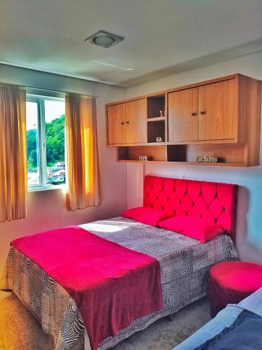 a bedroom with a large bed with a red head board at Brisa do Vale Loft 802 - Prox Centro e Oktoberfest - Piscina e WiFi in Blumenau