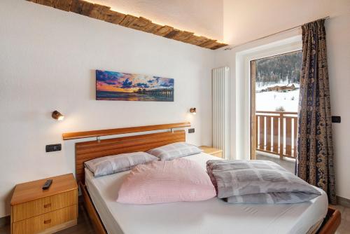 a bedroom with a bed and a large window at Casa Nicoletta inverno in Livigno