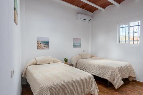 two beds in a room with white walls at Santa Clara Home in Marchena