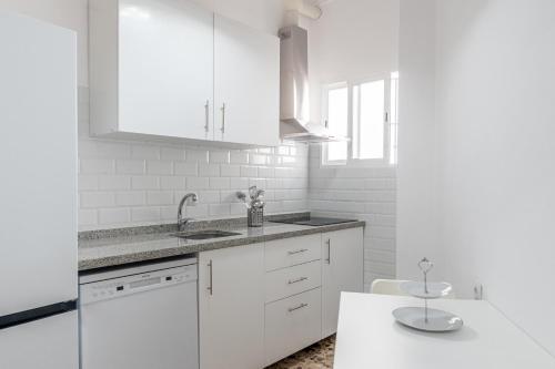 a white kitchen with white cabinets and a sink at Santa Clara Home in Marchena